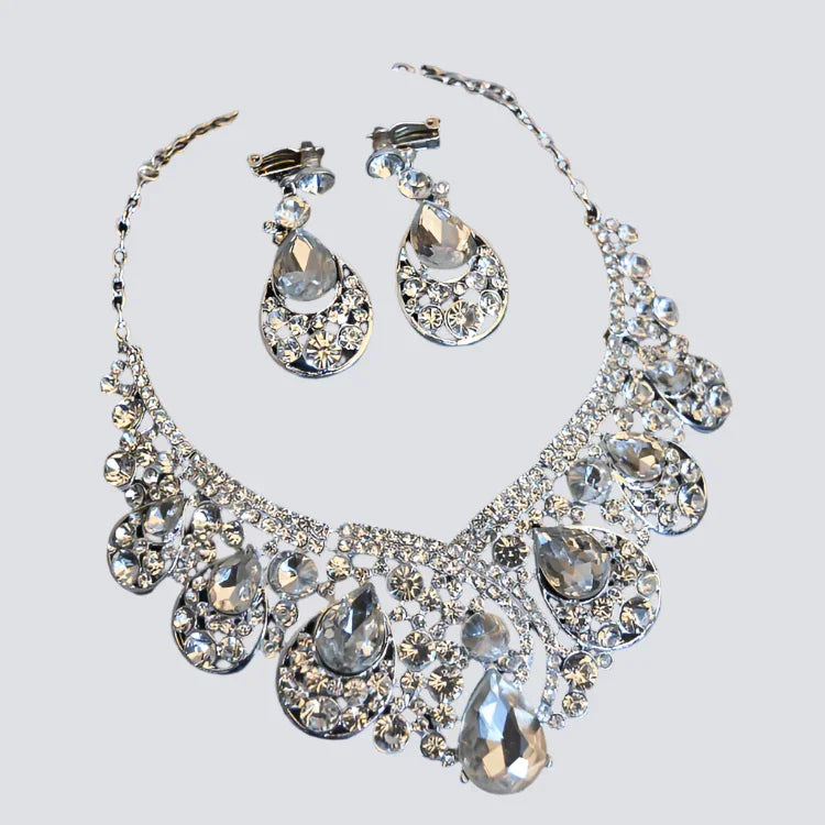 Silver crystal teardrop necklace and matching earrings set on light background