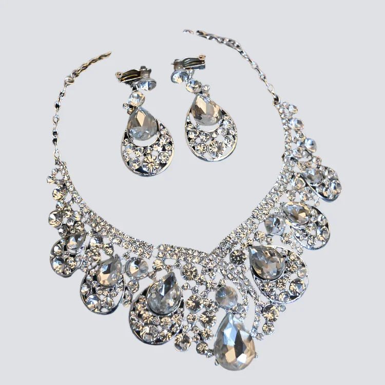 Silver crystal teardrop necklace and matching earrings set on light background