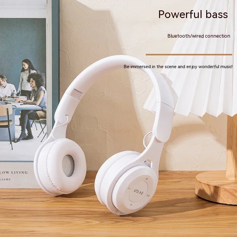 White wireless Bluetooth headphones with powerful bass on wooden table next to modern lamp and framed photo