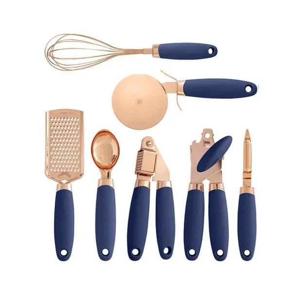 Set of rose gold kitchen utensils with navy blue handles including whisk, pizza cutter, grater, spoon, garlic press, can opener, and vegetable peeler