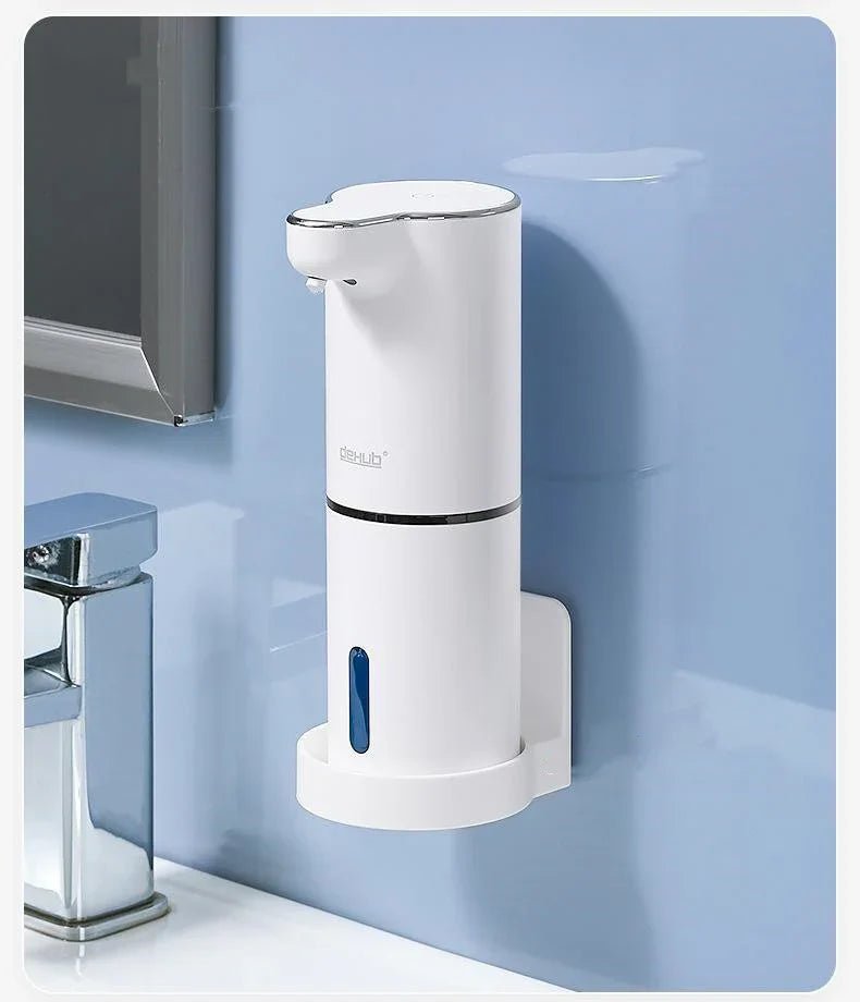 White automatic soap dispenser mounted on bathroom wall near faucet with blue background