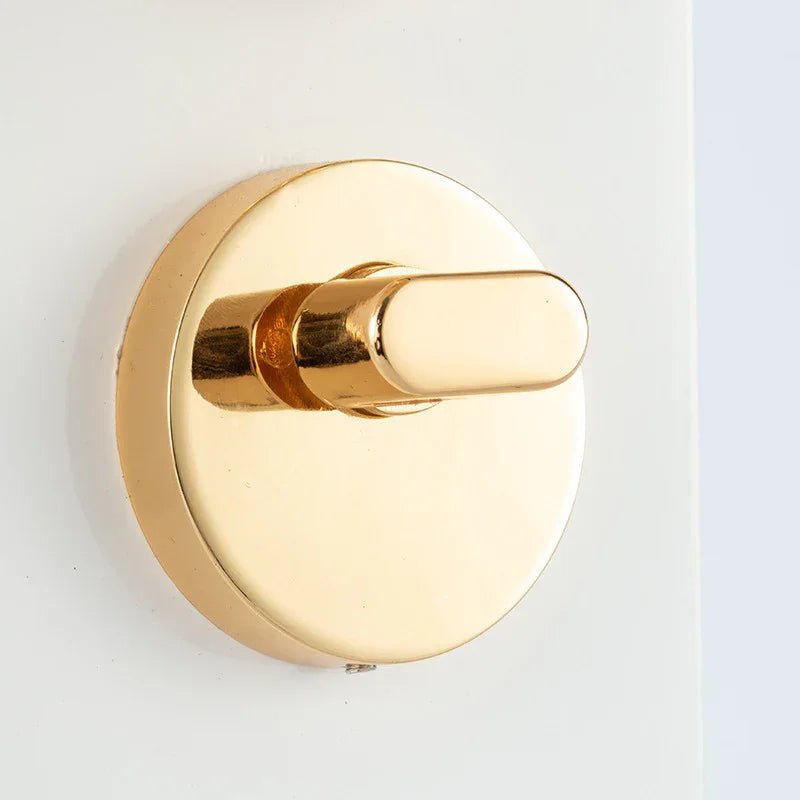 Close-up of shiny gold round door lock thumbturn on white door