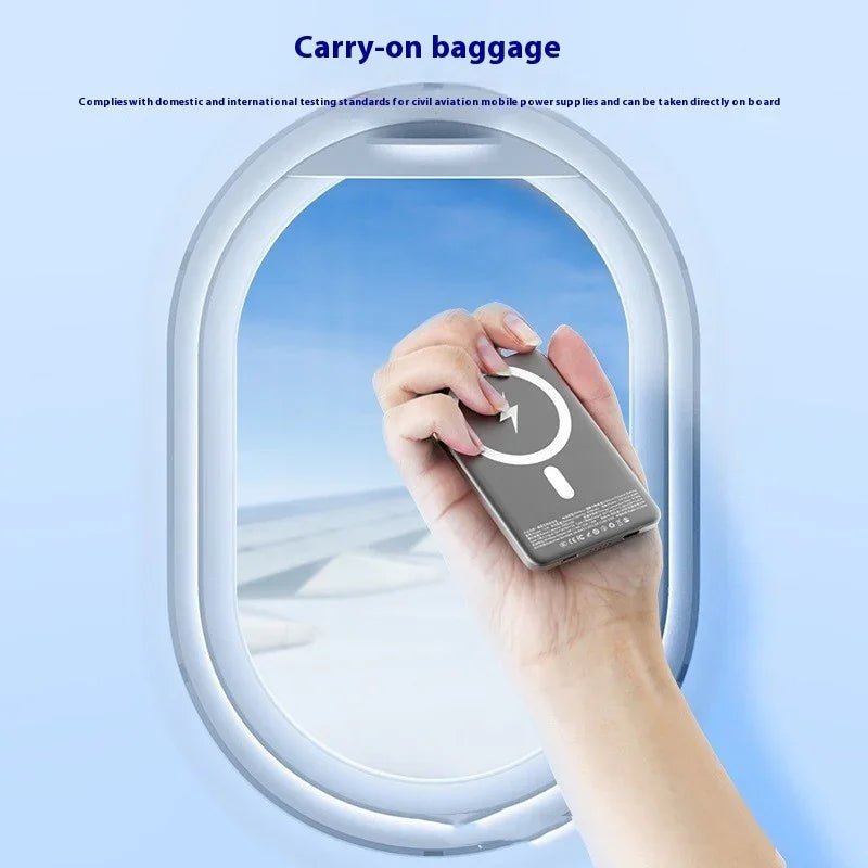 Hand holding portable power bank with wireless charging symbol in airplane window frame for carry-on baggage