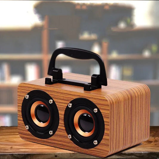 Portable wooden Bluetooth speaker with dual copper-accented drivers and black handle on wooden surface